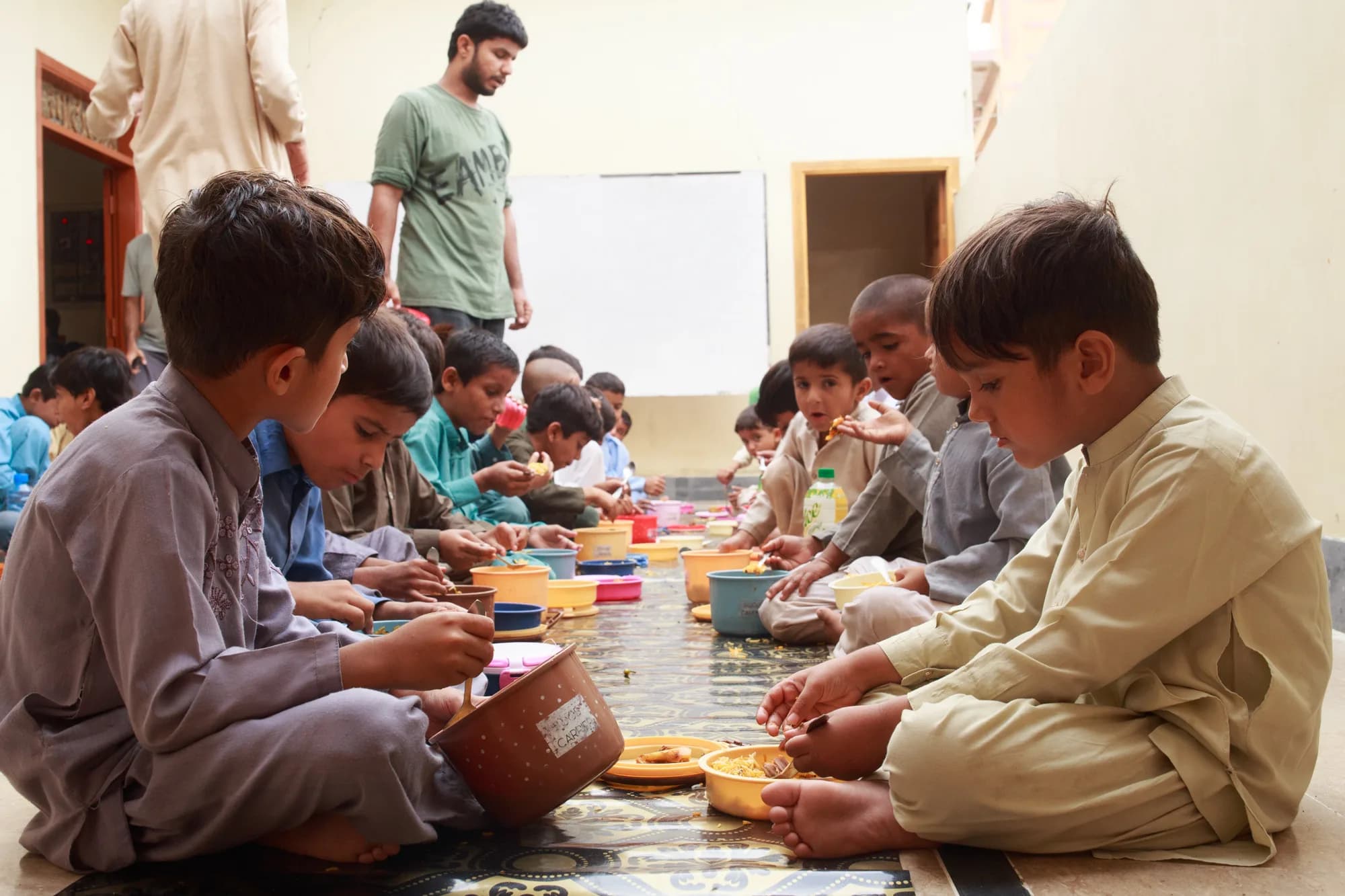 Expanded group of children being served meals at Library of Ibrahim Goth
